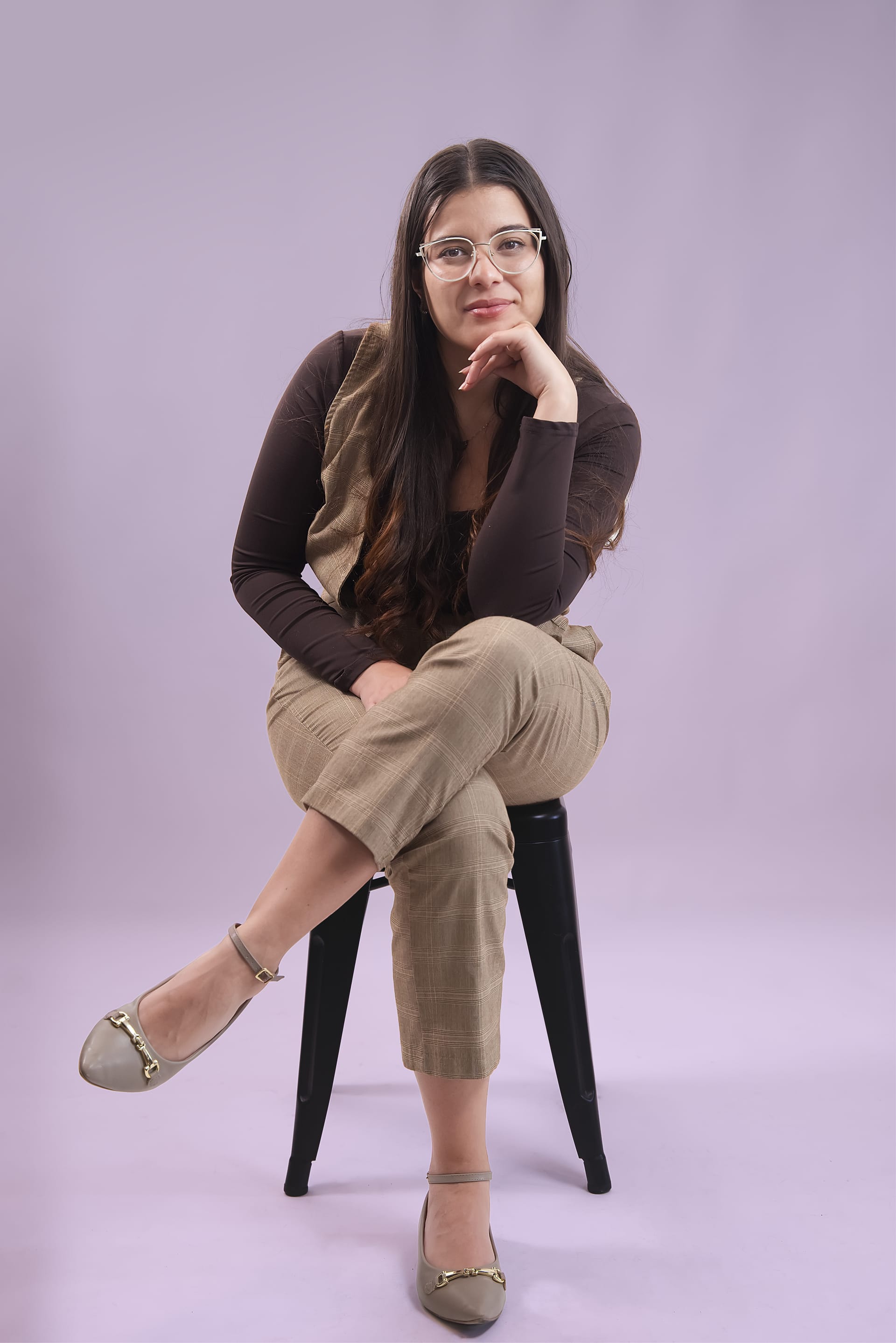 Nicole Castaño con gafas, sentada en un banco alto, pensativa